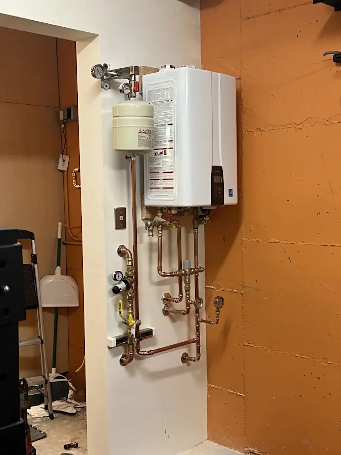 Plumbing technician inspecting water heater connections in Dracut